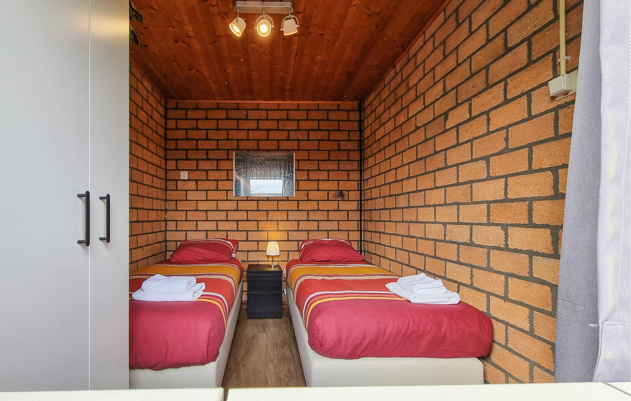 A room with two beds, a window, and a wooden ceiling.