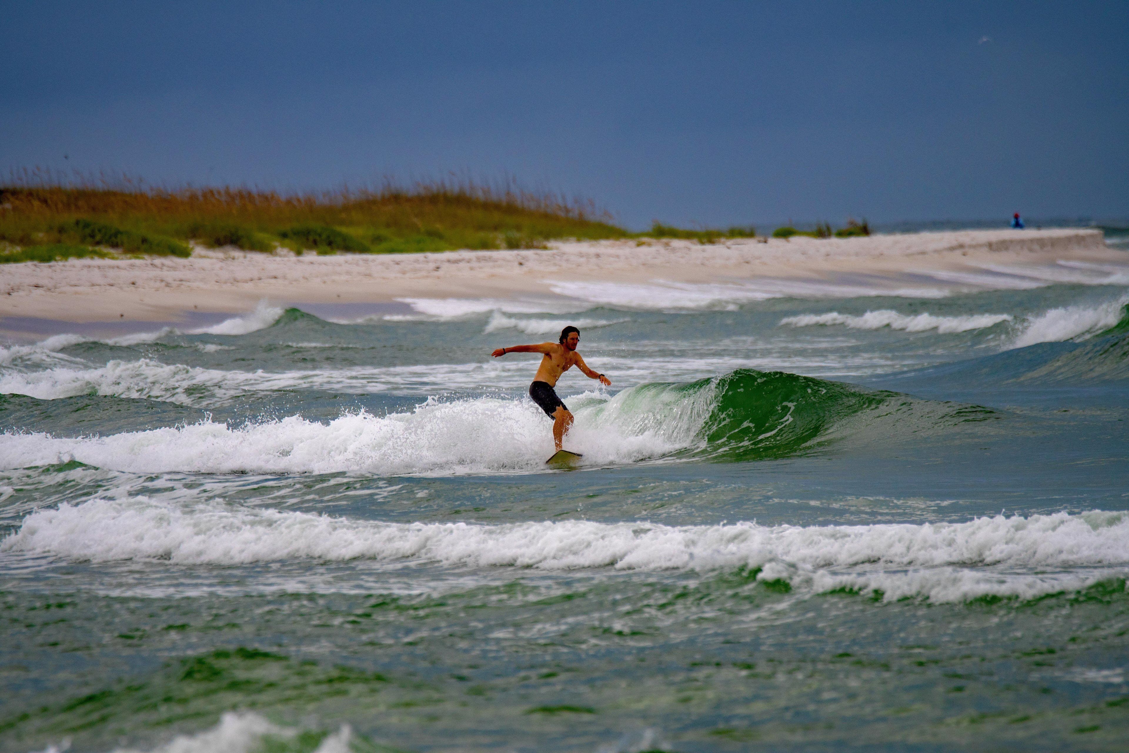 A beach scene with a surfer riding a wave.