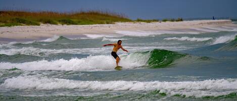 A beach scene with a surfer riding a wave.