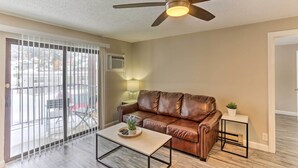 A living room with a brown leather sofa, a coffee table, a side table with a plant, and a ceiling fan. - Lead Condo w/ Patio: 14 Mi to Sturgis Rally (Lead)