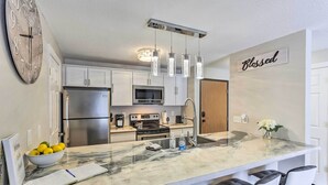 A modern kitchen with a marble island, stainless steel appliances, pendant lighting, and a 'Blessed' sign on the wall. - Lead Condo w/ Patio: 14 Mi to Sturgis Rally (Lead)