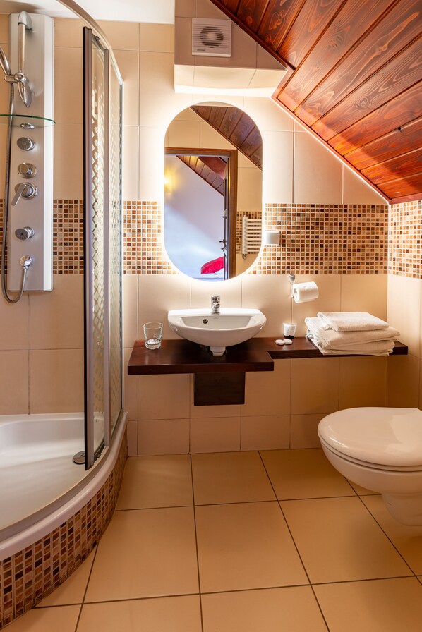 Un baño moderno con ducha de vidrio, un lavabo blanco y un inodoro.