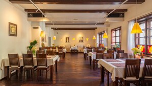 Un comedor amplio con mesas y sillas de madera, ventanas grandes y lámparas colgantes.