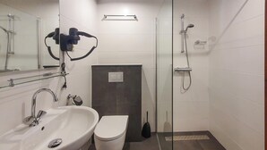 Een moderne badkamer met een wastafel, toilet en douche.