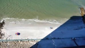 Vista aérea de una playa con algunos paraguas y gente.