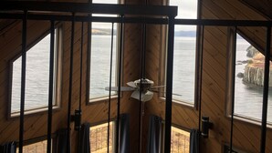A room with large windows offering a view of the sea and cliffs.
