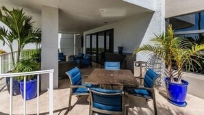 Une terrasse extérieure avec une table et des chaises, entourée de plantes en pot.