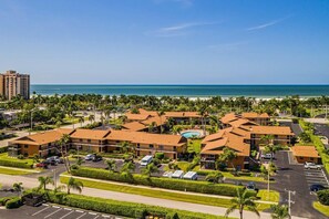 Um resort com várias construções, piscina e vista para a praia.