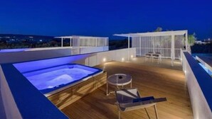 A rooftop terrace with a hot tub, wooden flooring, and a covered seating area with a view of the city at night. - Stunning home in Marina di Ragusa (Marina di Ragusa)