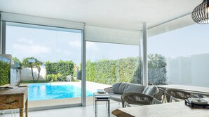 A modern outdoor living area with a pool, a dining table, and comfortable seating. - Stunning home in Marina di Ragusa (Marina di Ragusa)