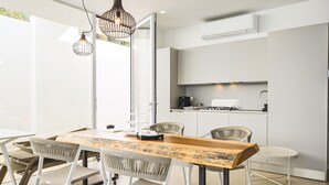 A modern dining area with a wooden table, white chairs, and pendant lighting. - Stunning home in Marina di Ragusa (Marina di Ragusa)