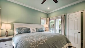 Une chambre avec un grand lit, une table de chevet, une lampe et une porte donnant sur un balcon.