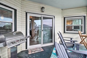Ein überdachter Patio-Bereich mit Grill, Schiebeglasfenstern und Gartenmöbeln.
