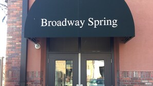 Entrada de un edificio con un letrero que dice "Broadway Spring" sobre una puerta doble.