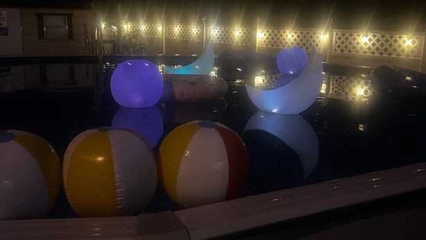 Zona de piscina con pelotas de playa hinchables y una fuente de agua.