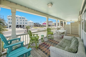 A covered porch with outdoor furniture, a view of the street, and buildings in the background.