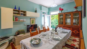 Un coin repas avec une table dressée pour quatre personnes, un téléviseur et un meuble avec des portes en verre.