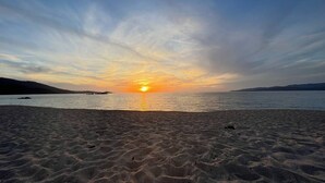 Una platja amb un atardeciment sobre l'aigua.