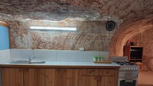 Eine Küche mit einer Holzinsel, einem Spülbecken, einem Herd und einer gefliesten Rückwand.