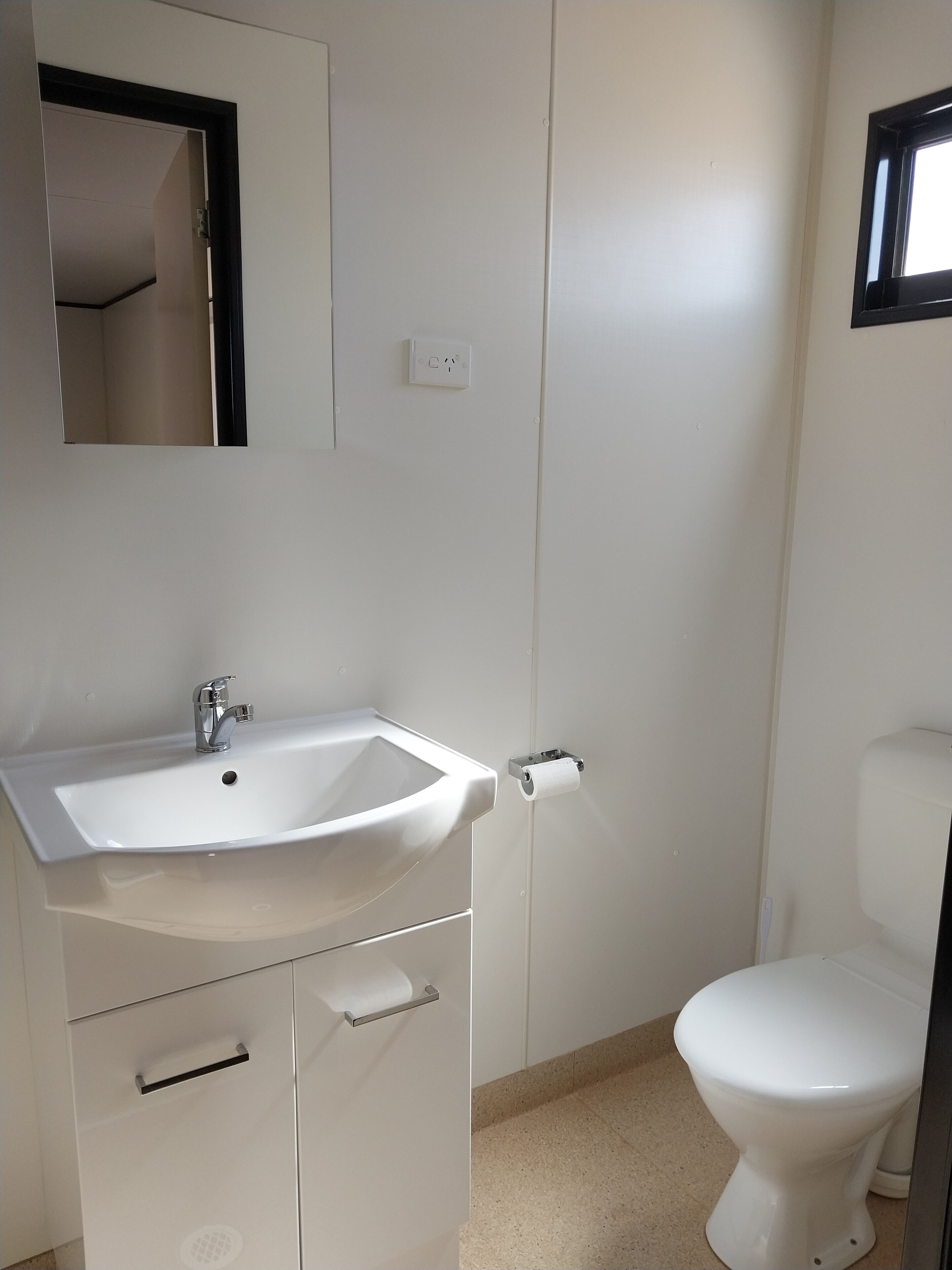 A bathroom with a white sink, a mirror, a toilet, and a door.