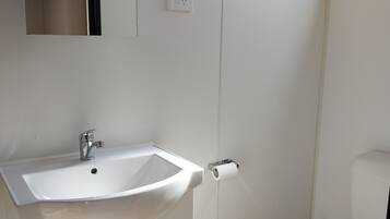 A bathroom with a white sink, a mirror, a toilet, and a door.