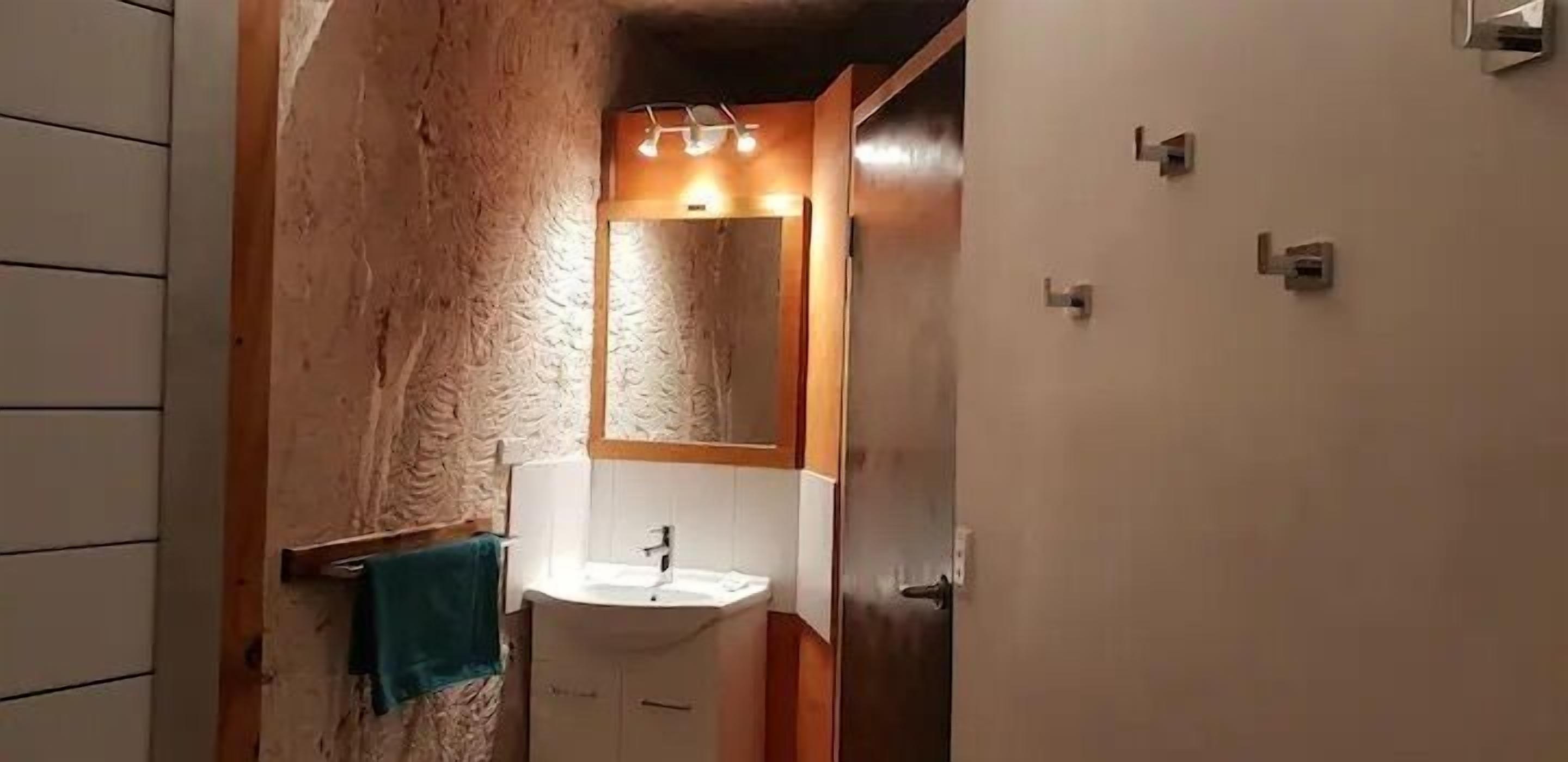 Un baño con pared de madera, un lavamanos blanco y un espejo.