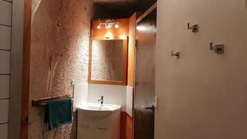 Un baño con pared de madera, un lavamanos blanco y un espejo.