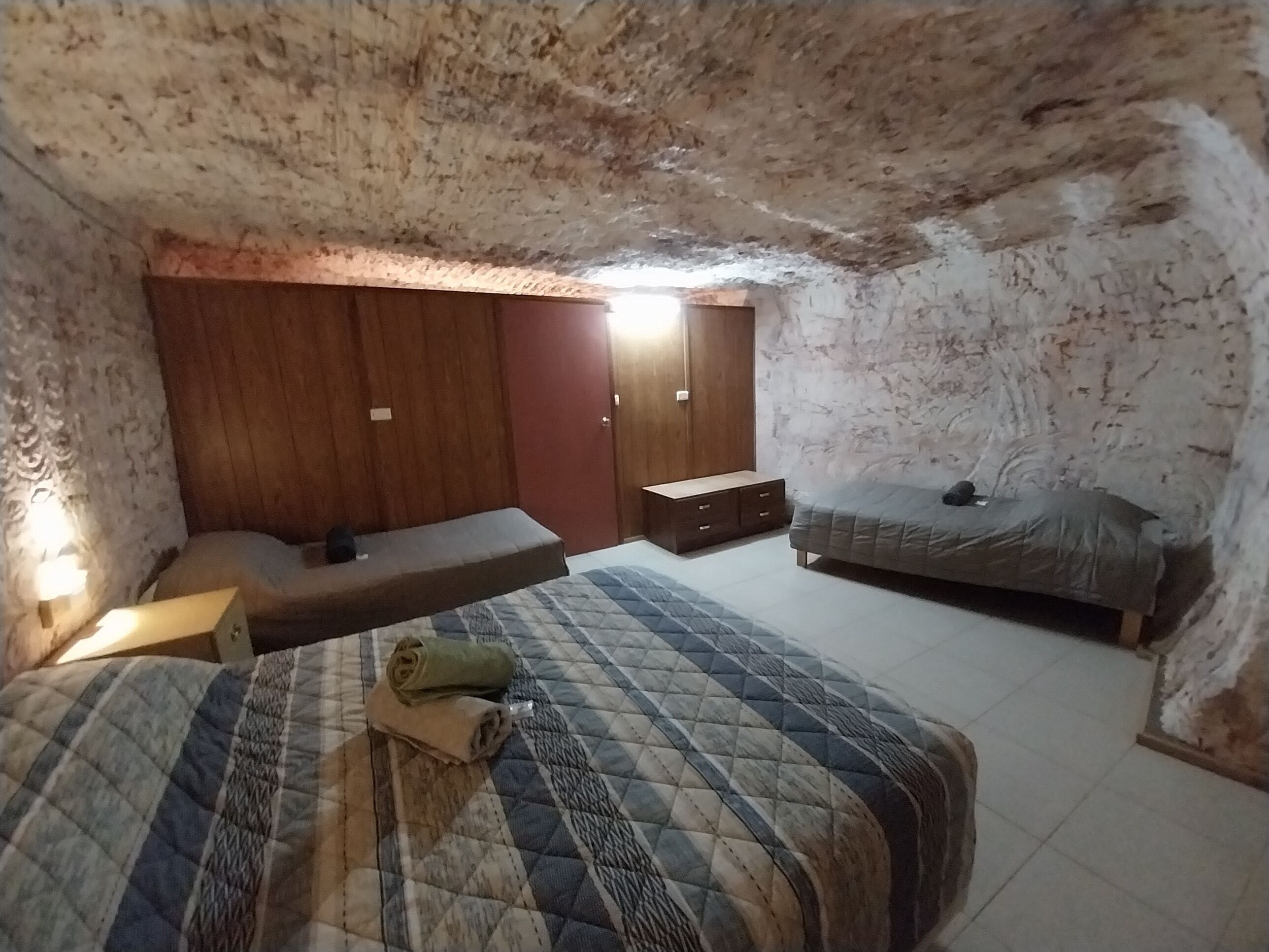 A bedroom with a bed, a bench, a wardrobe, and a nightstand.