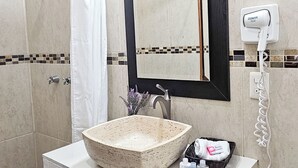 A bathroom with a stone sink, a mirror, a towel rack, and a hand dryer. - La Familia Hotel y Restaurante   (San Blas)
