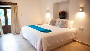 A bedroom with a bed, a window with curtains, a wall-mounted light fixture, and a flower vase. - La Familia Hotel y Restaurante   (San Blas)