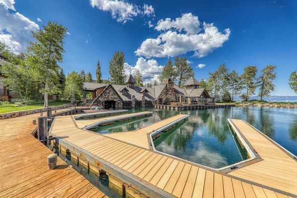 A wooden deck with a swimming pool, surrounded by lodge-style buildings with sloped roofs.