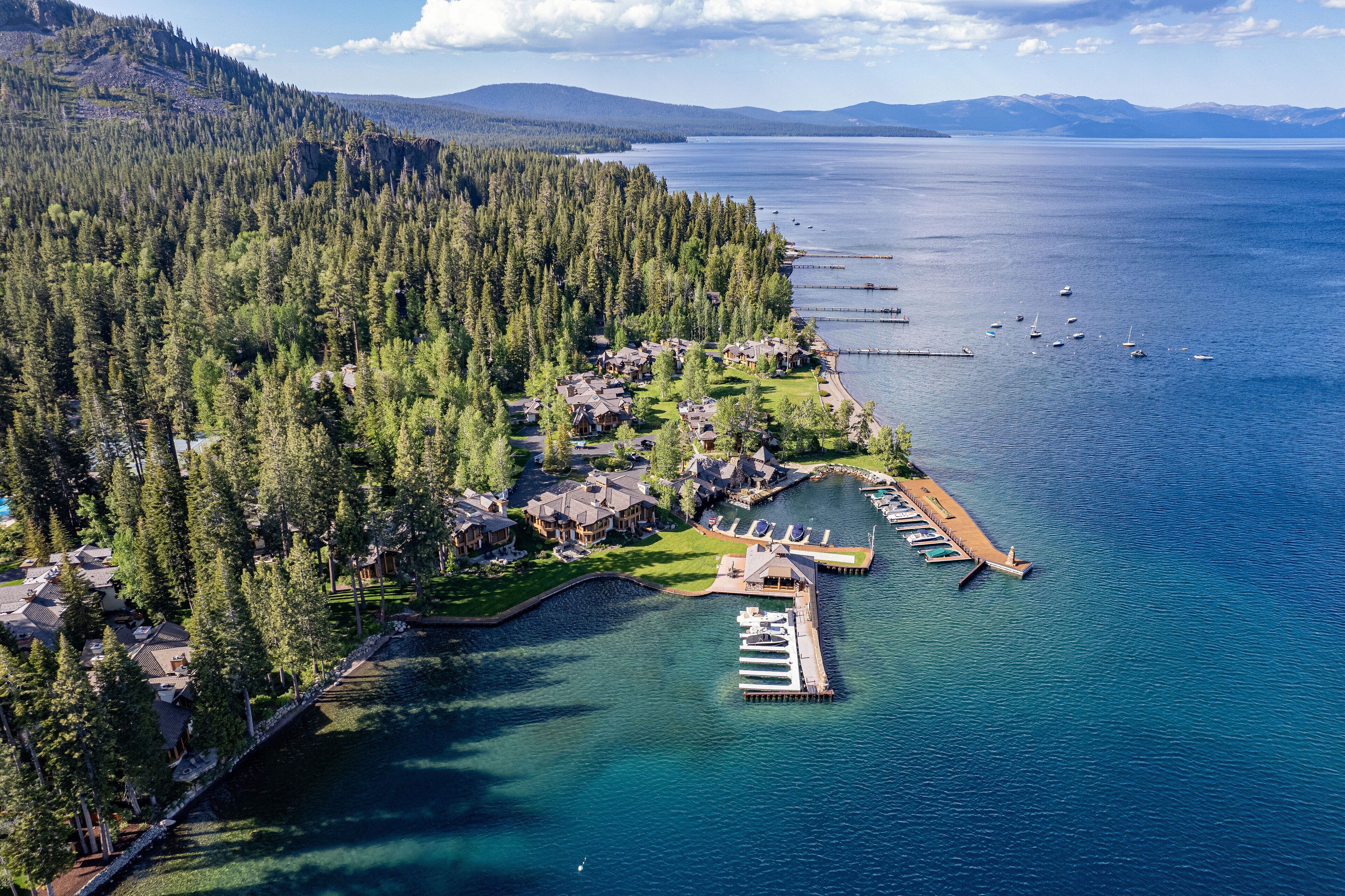 An aerial view of a lakeside resort with multiple cabins, a dock, and a beach.