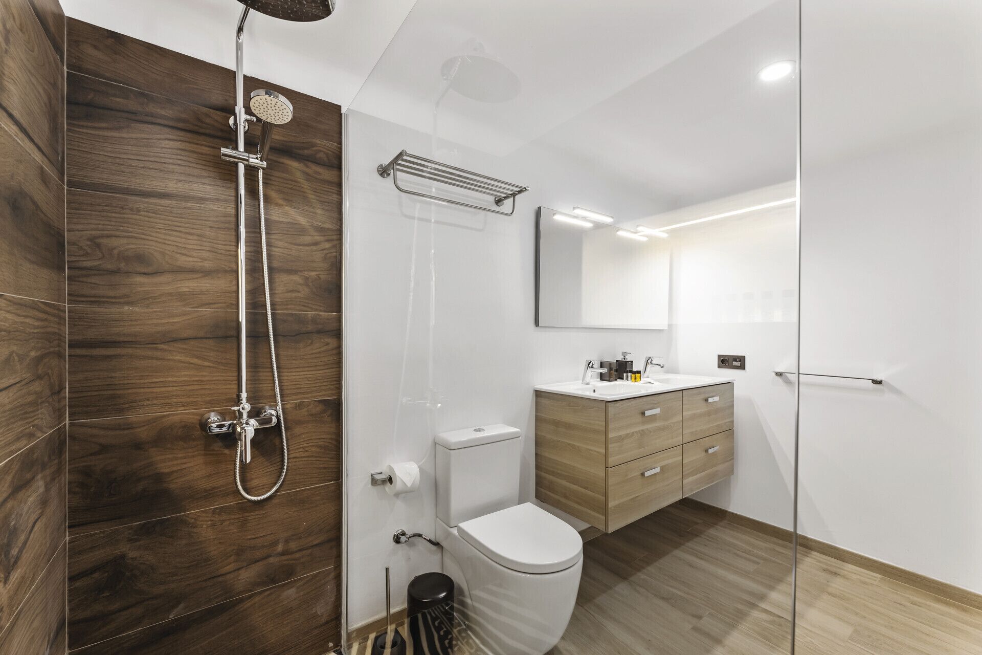 Une salle de bain moderne avec une cabine de douche en bois, des toilettes, un lavabo avec un miroir et un meuble de rangement.