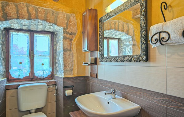 A bathroom with a stone wall, a window, a sink, and a mirror. - Beautiful home in Labin (Labin)