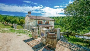 A stone building with a tiled roof, surrounded by a fence and greenery. - Beautiful home in Labin (Labin)