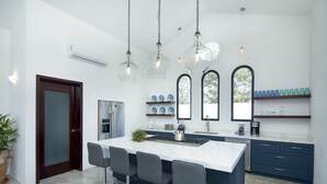 A modern kitchen with a central island, bar stools, and pendant lighting. - Private, ocean view, gourmet kitchen (Sayulita)