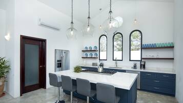 A modern kitchen with a central island, bar stools, and pendant lighting.