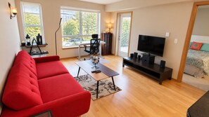 Una sala de estar moderna con un sofá rojo, una mesa de centro, un televisor y un comedor con una mesa y sillas.