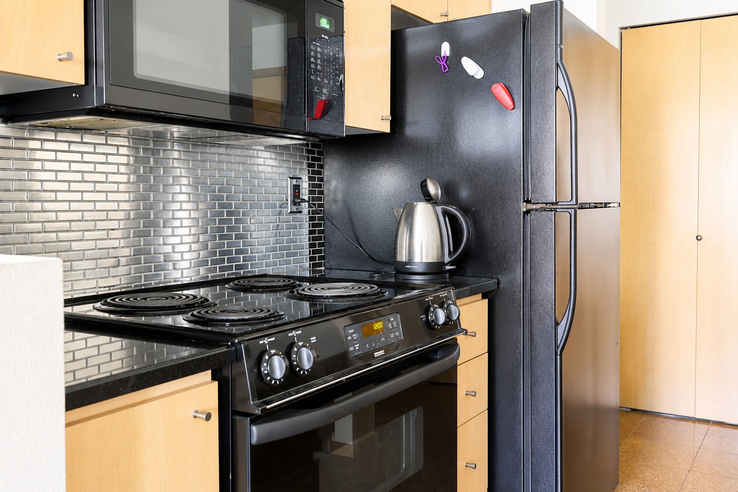 A kitchen with a black stove, a microwave, and a refrigerator.