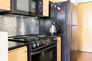 Een keuken met een zwart fornuis, een magnetron en een koelkast.