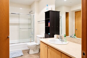 Un baño moderno con cabina de ducha de vidrio, inodoro, lavabo con espejo y mueble negro.