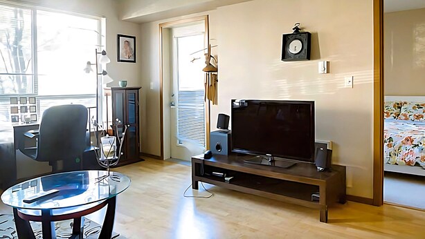Een moderne woonkamer met een flatscreen televisie, een glazen salontafel en een houten tv-meubel.