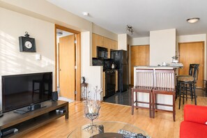 A modern living room with a flat-screen TV, a glass coffee table, and a red sofa. - 1BR near Swedish & Harborview, Free Garage Parking (Seattle)