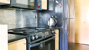 Een keuken met een zwart fornuis, een roestvrijstalen koelkast, en een magnetron boven het fornuis.