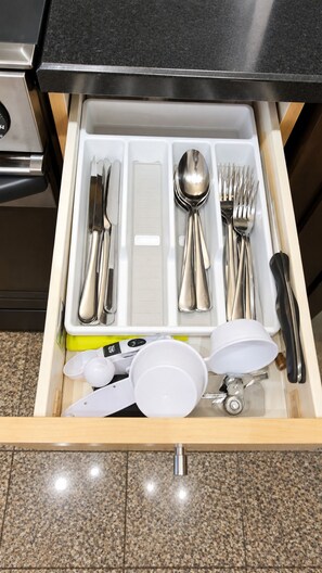 A drawer with neatly organized kitchen utensils including spoons, forks, and a knife.