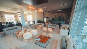 A spacious lobby with multiple seating areas, large windows, and a modern interior design. - ENTRE VIÑEDOS RESORT HOTEL  (Schaqui)