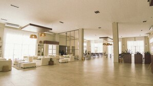 A spacious lobby with white sofas, a coffee table, and potted plants. - ENTRE VIÑEDOS RESORT HOTEL  (Schaqui)