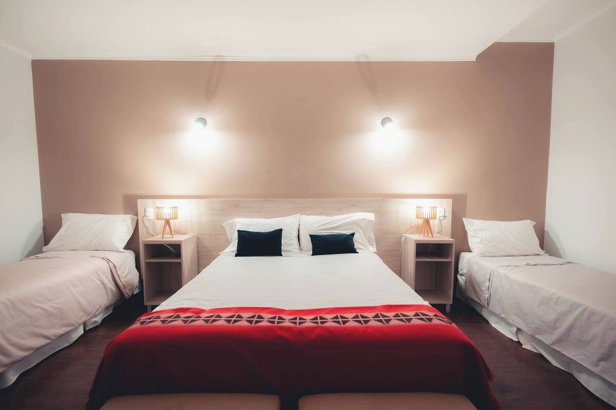 A hotel room with a large bed, two bedside tables, and two lamps.
