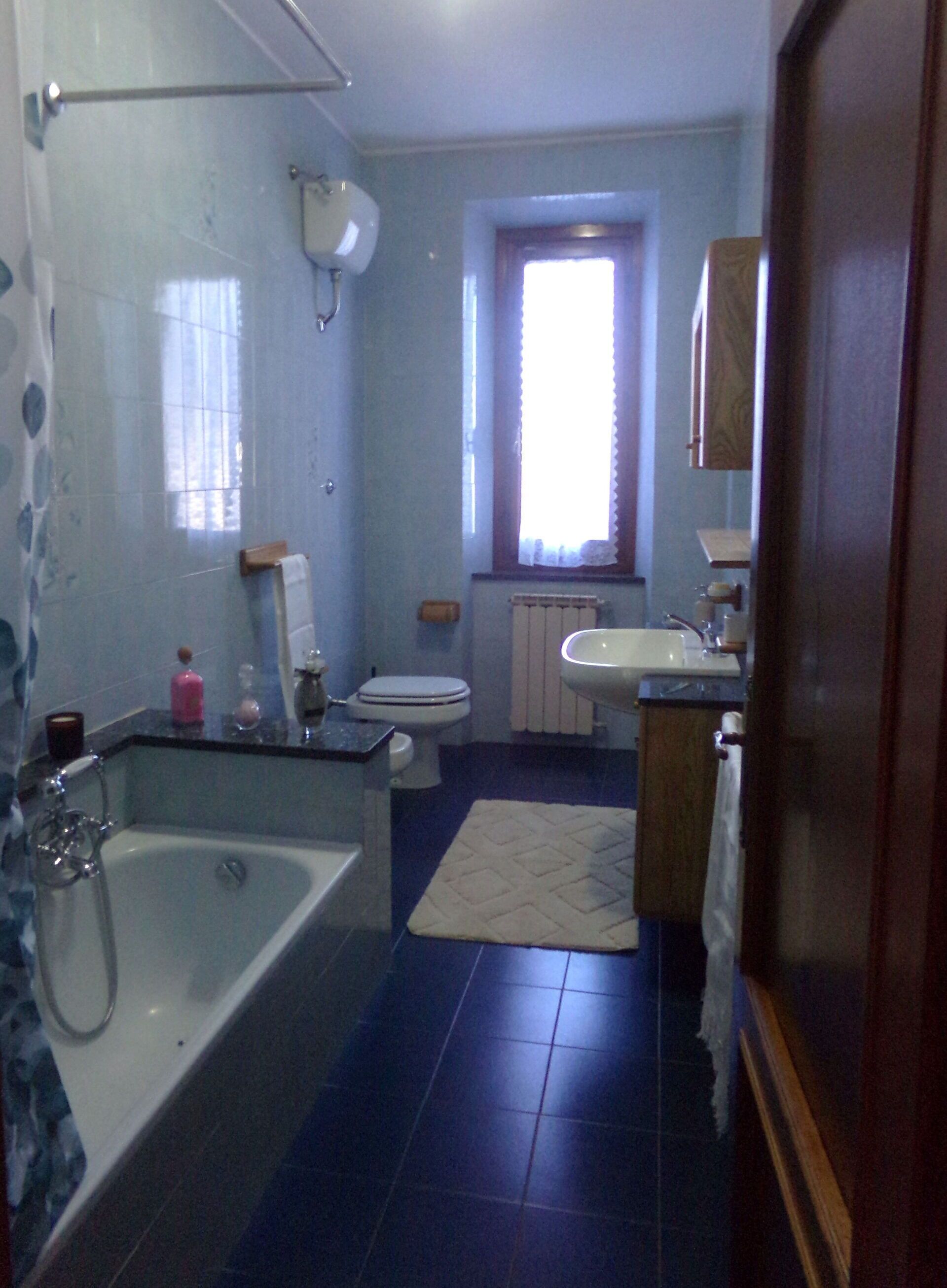 A bathroom with a bathtub, toilet, sink, and a window.
