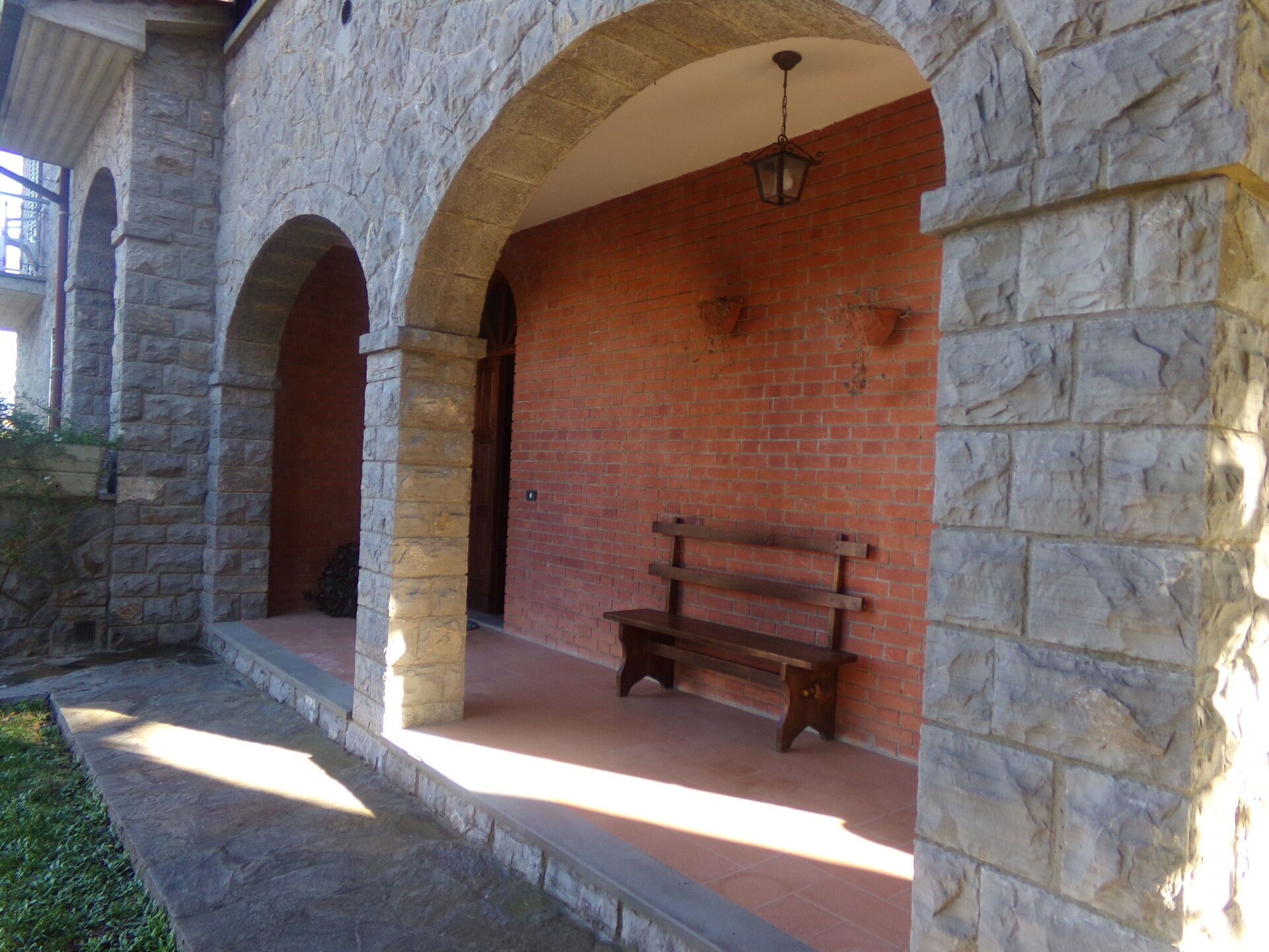 A stone building with a brick wall and a wooden bench.